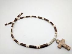 "Natural coconut and bone cross necklace by JT Maui. This unisex cross necklace is a comfortable and lightweight 5-6 mm width, great for all ages. QUALITY: Hand beaded on multi strand stainless steel beading wire, completed with picture jasper stone cross on white bone and natural coconut. Please note all stones and bone are natural color variations. No two crosses or materials are exactly alike. We believe in rugged and natural. Our custom chokers are an especially great gift idea for men or bo Adjustable White Cross Necklaces, Adjustable White Cross Necklace, Baby Boy Necklace Cross, Male Cross Necklace, Brown Cross Necklace With Wooden Beads, Wood Cross Necklace Men, Necklace Boys, Handmade Brown Crucifix Necklace, Boys First Communion