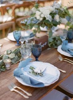 the table is set with blue and white plates, silverware, napkins, and flowers