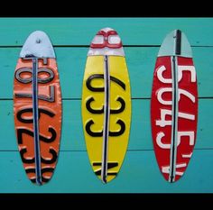 three surfboards are hanging from the side of a wall with numbers painted on them