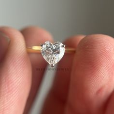 someone is holding a heart shaped diamond in their hand