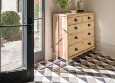 a chest of drawers sitting in front of a window next to a black and white checkered floor