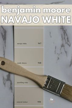 a paint brush sitting on top of a table next to a white swatch with the words, benjamin moore navajo white