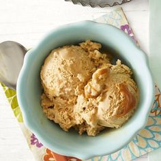 a blue bowl filled with ice cream on top of a colorful place mat next to a spoon