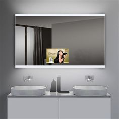 a bathroom vanity with two sinks and a large mirror above it that has a woman taking a selfie in the mirror