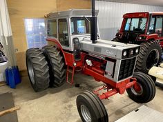 two large tractors are parked in a garage