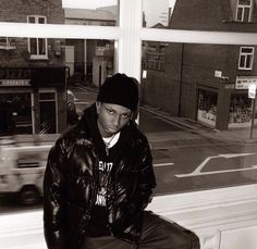 a black and white photo of a man sitting on a window sill