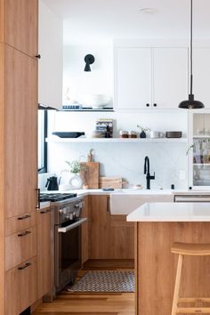 a kitchen with wooden floors and white cabinets, an island countertop and stools