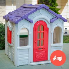 an outdoor play house with purple roof and red door