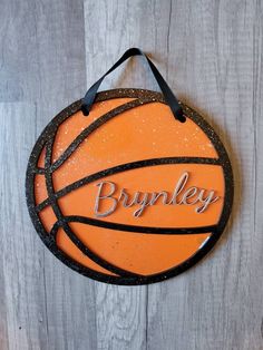 an orange and black basketball with the word brumley on it hanging from a wooden wall