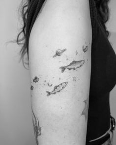 a black and white photo of a woman's arm with fish, stars and planets on it