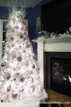 a white christmas tree in front of a fireplace