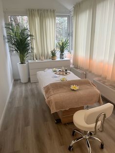 a spa room with two massage tables and flowers on the top of each table, in front of a large window