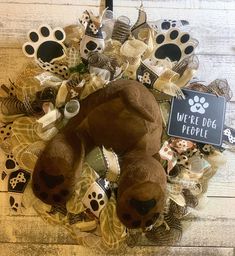 a teddy bear wreath on top of a wooden floor next to a sign that says, we're dog people