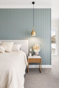 a bedroom with blue walls and white bedding in the corner, along with a wooden nightstand