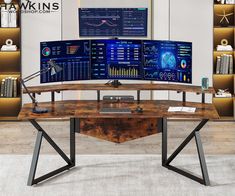 a computer desk with two monitors on top of it and bookshelves in the background