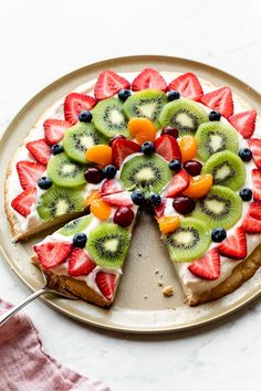 a fruit pizza on a plate with a slice cut out and ready to be eaten