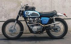 a blue and black motorcycle parked in front of a building with concrete walls behind it