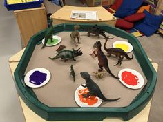 an assortment of toy dinosaurs on display in a classroom