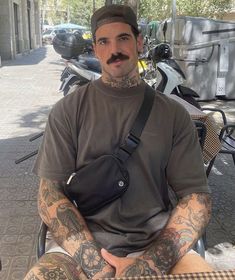 a man with tattoos sitting on a bench in front of some parked scooters