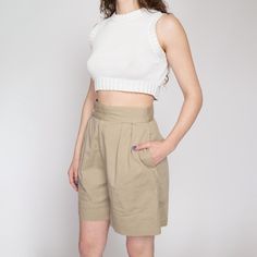 Vintage 80s high waisted khaki cotton shorts with pleating at the front. They have a zipper fly and two inner and outer buttons at the waist for closure. Great for a curvy fit! Measurements and Condition: Fits like: Labeled size 8, fits modern women's small to medium (see waist measurement to ensure fit) Fabric: Cotton Brand: Charter Club Condition: Very good, with light general wear Waist: 27" Hips: 46" - taken at the bottom of the zipper opening Rise: 14.25" Inseam: 7" Hem allowance: 2.5" Shown on a 5'8" model with measurements of 35"-26"-38", usually wears a size small to medium. See our FAQ for more info on sizing and condition ratings. High-waisted Khaki Shorts For Work, Khaki Shorts For Workwear, Khaki Workwear Shorts, High Waist Shorts With Pockets For Daywear, Chic High-waisted Khaki Shorts, Spring Khaki Shorts With Short Inseam, Khaki High-waist Relaxed Fit Shorts, Khaki High Waist Relaxed Fit Shorts, High Waist Khaki Shorts Relaxed Fit