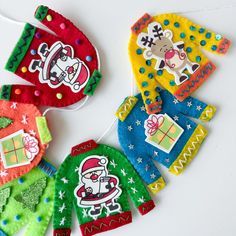 colorful felt ornaments are hanging on a white table with string attached to the top and below them