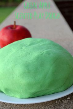 two green and red doughnuts on a plate with an apple in the background