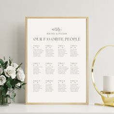 a wedding seating chart with white flowers on a table next to a gold candle holder