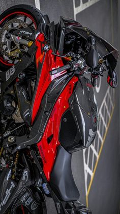 a red and black motorcycle parked next to a wall