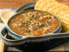 a blue bowl filled with soup next to a piece of bread on top of a table