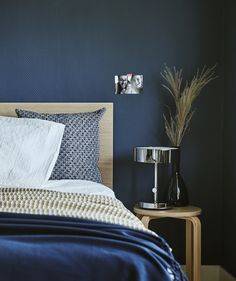 a bed in a bedroom with blue walls and white linens on the headboard