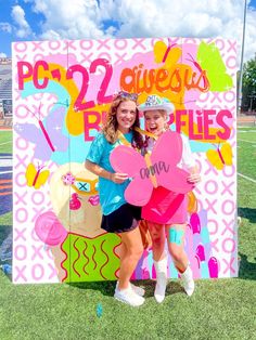 two girls standing in front of a sign with hearts