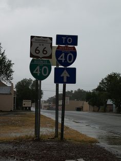 several street signs on poles in front of a road