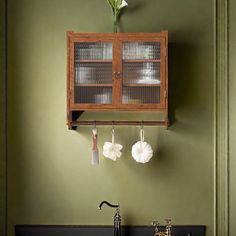 a kitchen with green walls and black counter tops, an old fashioned sink and wooden cabinet above it