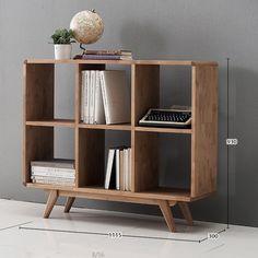 a book shelf with books on it next to a plant and a wall mounted clock