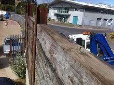 a blue and white truck parked next to a wooden fence on the side of a road