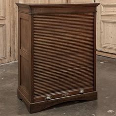 a wooden cabinet sitting in the middle of a room next to a wall with wood paneling on it