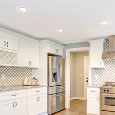 a kitchen with stainless steel appliances and white cabinetry, including a stove top oven