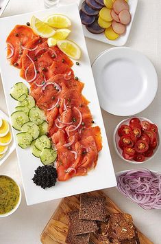 a white plate topped with sliced up salmon and veggies next to other foods