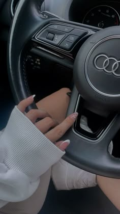 a woman holding the steering wheel of a car with her hands on the steering wheel