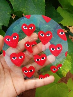 a hand holding a glass ball with lots of red hearts on it and eyes in the middle