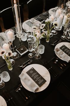 the table is set with black and white linens, silverware, candles, and flowers