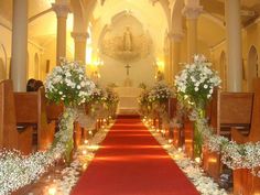 an aisle decorated with flowers and candles for a wedding ceremony at the end of a church