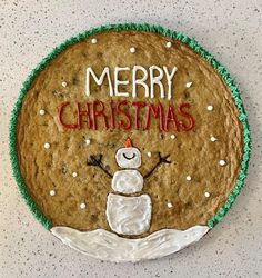 a cookie decorated like a snowman with merry christmas written on it