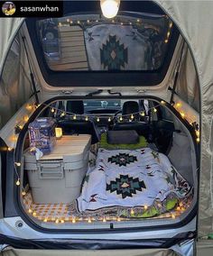 an open car trunk with lights and blankets in it