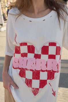 Distressed, garment washed graphic t-shirt Vintage-style, checker Valentine heart graphic with "Cherry" text. Torn and distressed detailing at neckline, cuffs, and hem. Round neckline. Short sleeves. Drop shoulder. Oversized fit. 100% Cotton. Imported top designed and printed in LA. Model wears size S. Distressed Graphic Tee, Heart Graphic, Iron Decor, Valentine Heart, Drop Shoulder, Round Neckline, Vintage Style, Graphic T Shirt, Tops Designs