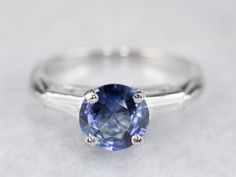 This vintage sapphire and diamond engagement ring is the epitome of a classic! This intense blue sapphire is a perfect, rich color, the benchmark for a fine sapphire. The crisp blue hue is filled with glitter and it has phenomenal light refraction, depth of color, and sparkle on the finger! We've set this in a tasteful platinum mounting featuring baguette diamonds on either side, equal in quality and sparkle to this lovely center sapphire. The ring was originally designed as an engagement piece, Platinum Engagement Rings Vintage, Sapphire And Diamond Engagement Ring, Light Refraction, Vintage Engagement Rings Sapphire, Platinum Engagement Ring, Ring Sapphire, Vintage Sapphire, Engagement Ring Vintage, Baguette Diamonds