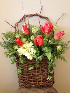 a basket filled with flowers sitting on top of a wooden table next to a wall