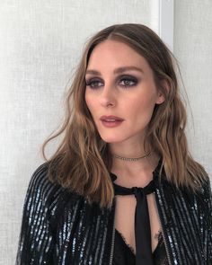 a woman with long hair wearing a black tie and sequins shirt is looking at the camera