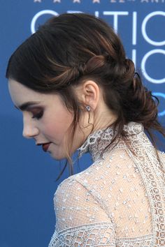 a woman with dark hair wearing a white dress and diamond earrings on her left ear