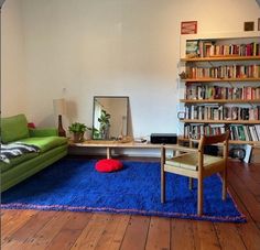 a living room filled with furniture and bookshelves next to a blue rug on the floor